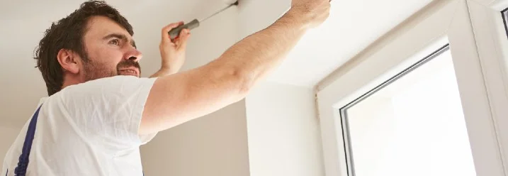 Person bringt mit Schraubendreher Rollladenkasten an